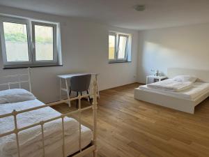 a bedroom with two beds and a desk and two windows at Großzügiges Apartment in Biberach an der Riss in Biberach an der Riß