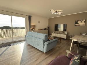 a living room with a blue couch and a television at Exceptionnel appartement avec vue mer in Vendres-Plage