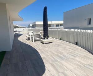 a patio with a umbrella and chairs and a table at Exceptionnel appartement avec vue mer in Vendres-Plage