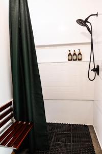 a shower with a green shower curtain next to a bench at Sunken Escapes Cabin 7 in New Minas +21 photos