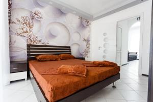 um quarto com uma cama grande com lençóis laranja em VIP Hotel em Koblevo