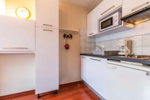 a kitchen with white cabinets and a microwave at Le Sapi 1E Balcon panoramique Aiguilles Rouges avec parking gratuit in Chamonix-Mont-Blanc
