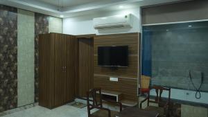 a living room with a tv and a entertainment center at Hotel Holiday Fun Resort in Prāgpura