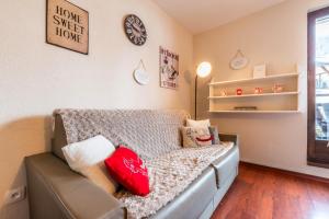 a room with a couch with pillows and a clock at Le Sapi 1E Balcon panoramique Aiguilles Rouges avec parking gratuit in Chamonix-Mont-Blanc +12 photos
