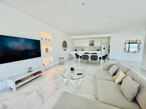 a white living room with a couch and a tv at Vila Pombal Tomar - Luxury Apartment with private pool and Castle View in Tomar +38 photos
