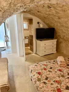 a bedroom with a tv on a dresser with a bed at La Cueva in La Garde-Adhémar
