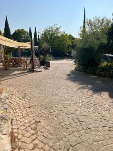 a patio with tables and umbrellas in a park at La Cueva in La Garde-Adhémar