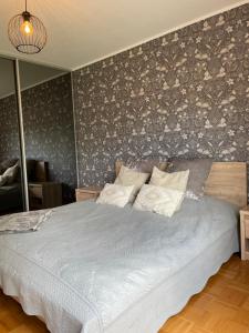 a bedroom with a large bed with a gray wall at Suur-Jõe apartment in Pärnu