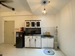una cucina con mobili bianchi e un frigorifero nero di Horizon suits sun suria sepang a Sepang