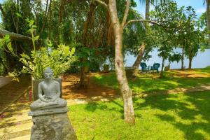 a statue sitting in the grass near a body of water at LAKE LOFT - La maison VEDA in Koggala