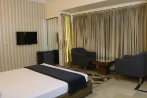 a hotel room with a bed and two chairs and a television at New Pak Guest House in Islamabad +22 photos