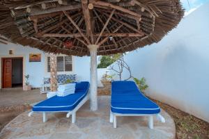 two blue chairs under an umbrella on a patio at Papa Romolo Villa's in Watamu