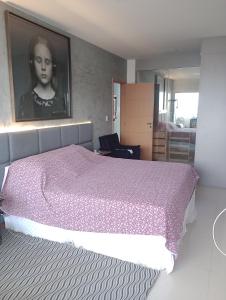 a bedroom with a pink bed with a picture on the wall at Luxury Apartment COP 30 in Belém