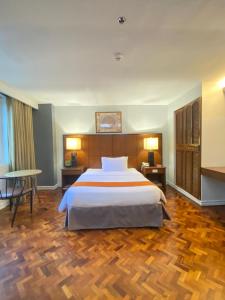 a bedroom with a large bed and a wooden floor at Comfy Inn Manila-Kalaw in Manila