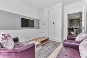 a living room with two purple chairs and a tv at Horison Haven in Roodepoort