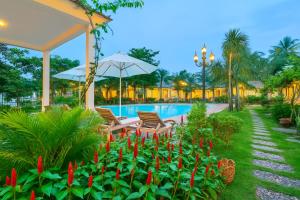 a resort with a pool and two chairs and red flowers at S79 Blue Paradise Lam Ha Pool in Phu Quoc