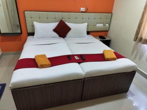 twee bedden in een kamer met oranje en wit bij VRJ Residency inn in Chennai
