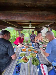 a group of people sitting around a table with food at Casa Matā Phitā Cottage in Patjung