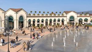 a group of people walking around a plaza with a fountain at La Maisonette Apartment with terrace - 2min to outlet in Serravalle Scrivia