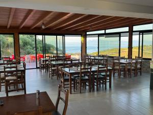 a restaurant with wooden tables and chairs and windows at Restorant Hotel Niku in Draç