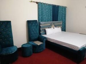 DargaiにあるGlobal Inn Guest Houseのベッドルーム1室(ベッド1台、青い椅子2脚付)
