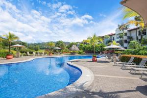 a swimming pool at a resort with chairs and umbrellas at Del Mar 5F 3 bdr Garden View in Los Suenos in Herradura