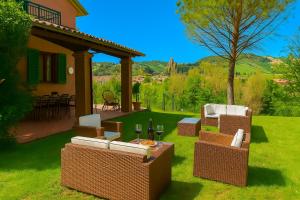 a patio with wicker chairs and a table with wine glasses at Villa delle rose Brisighella in Brisighella