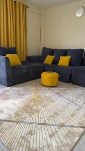 a living room with a blue couch and yellow pillows at Macedona in Narok