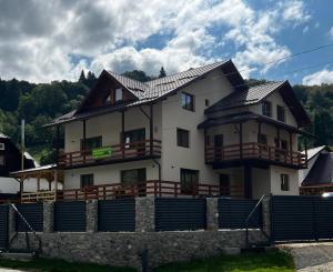 a large white house with a fence in front of it at Casa Bujor de Munte Dragoslavele in Dragoslavele