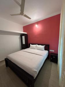 a bedroom with a large bed with a red wall at Le paradiso in Marayoor