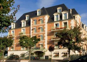 a large brick building with a black roof at La Closerie SPA & Résidence Hôtel in Deauville