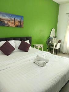Un dormitorio con una cama blanca con una pared verde. en Happy Pool Villa near Jomtien Beach on Thepprasit Road, en Pattaya South