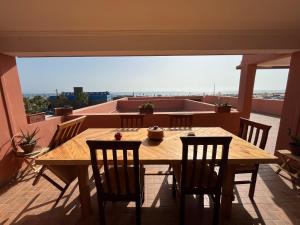 une table et des chaises en bois sur un balcon dans l'établissement Imi Beach House, à Agadir nʼ Aït Sa