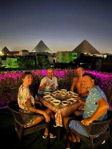 a group of people sitting at a table in front of pyramids at Jana pyramids view in 3 in Cairo