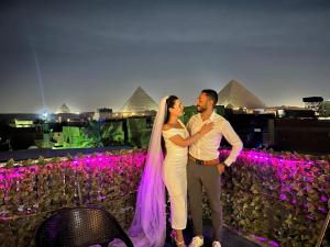 a bride and groom posing for a picture in front of the pyramids at Jana pyramids view in 3 in Cairo