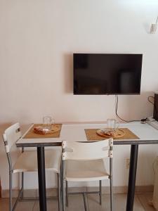 a dining room table with two chairs and a tv at Lourette se Plek in Sannieshof