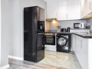 a kitchen with a black refrigerator and a washer and dryer at Apartment 1 - Uk50135 in Stoke on Trent
