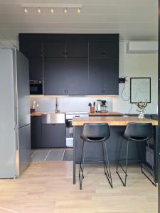 a kitchen with black cabinets and two bar stools at The lake house - boats, beach, sauna, dock and barbecue! in Sandviken +63 photos