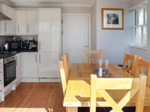 Una cocina con una mesa de madera y una cocina con gabinetes blancos. en Tideglass, en Penally