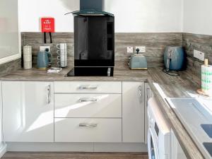 a kitchen with white cabinets and a black appliance at Cambusmoon Apartment in Gartocharn