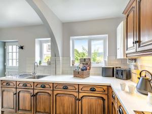 a kitchen with wooden cabinets and a sink and windows at Willoways in Bakewell