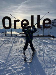 a person on skis in the snow in front of a sign at Sky High Family Apartment in Orelle