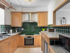 una cocina con armarios de madera y azulejos verdes en Sands, en Woolacombe