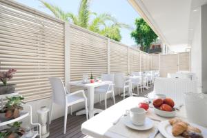 a restaurant with white tables and white chairs at Hotel Apollo in Riccione