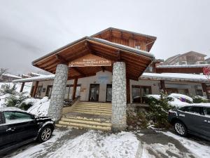a building with a porch with snow on it at Sky High Family Apartment in Orelle