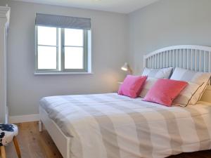a bedroom with a large bed with pink pillows at Hen Harrier Lodge-Uc3979 in Saint Columb Major +17 photos