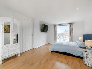 a white bedroom with a bed and a window at Beach House in Seaford +12 photos
