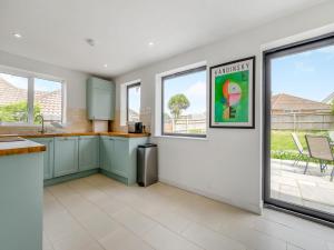 a kitchen with green cabinets and windows in a house at Beach House in Seaford