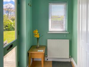 een vaas met bloemen op een tafel naast een raam bij Chy An Mordros in Hayle