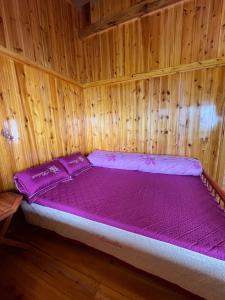 Una cama en una habitación de madera con un colchón morado. en Bau's Sapa Homestay, 